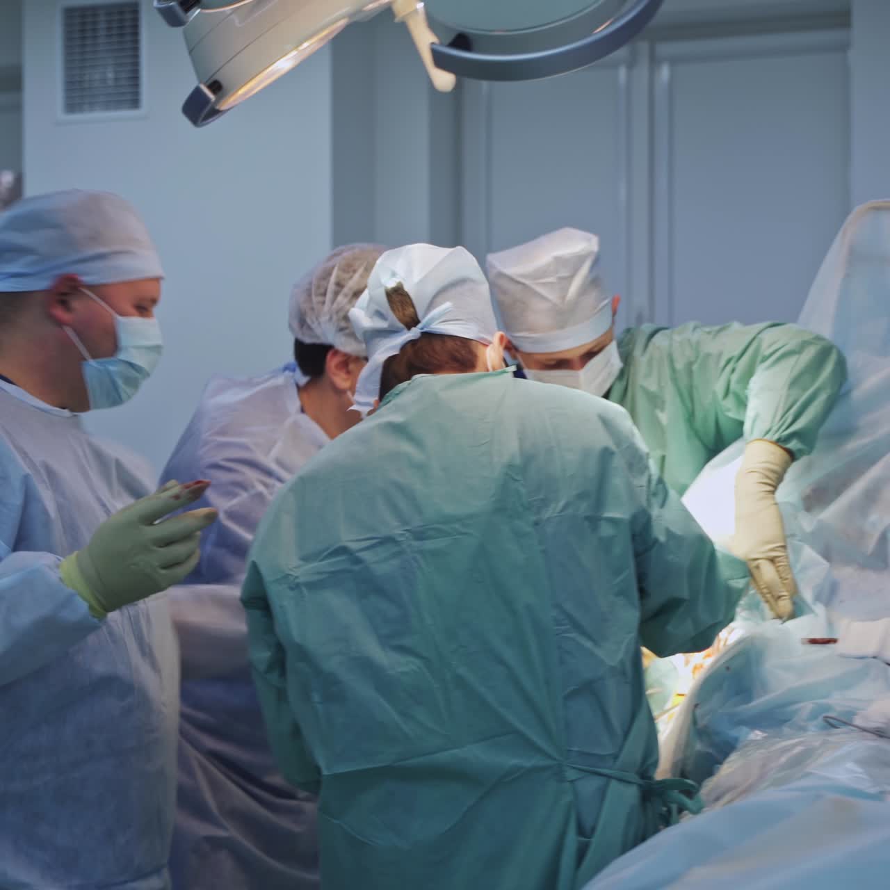 Big team of surgeons crowded over the operated patient. Male doctors conducting operation in up-to-date surgery room