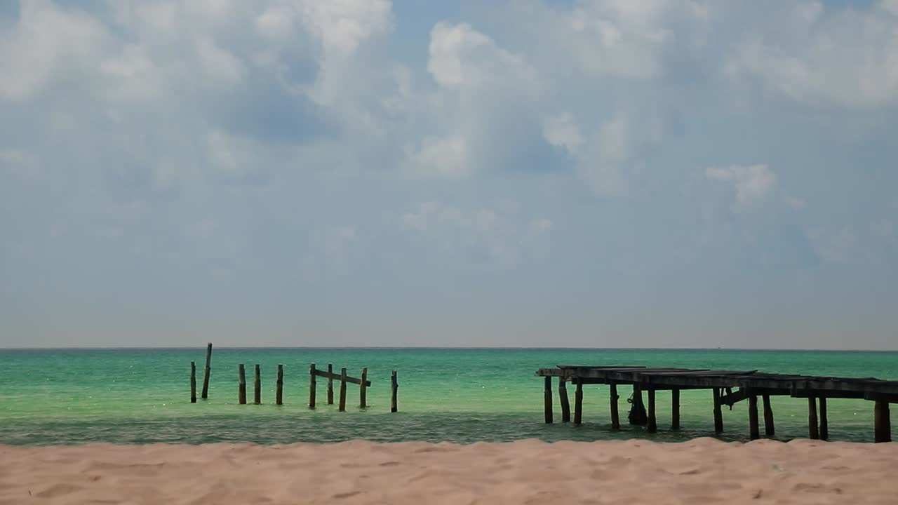 tiro largo de un paseo marítimo de madera roto en el vasto horizonte entre el mar azul y el cielo en la playa de soksan en la isla de koh rong camboya