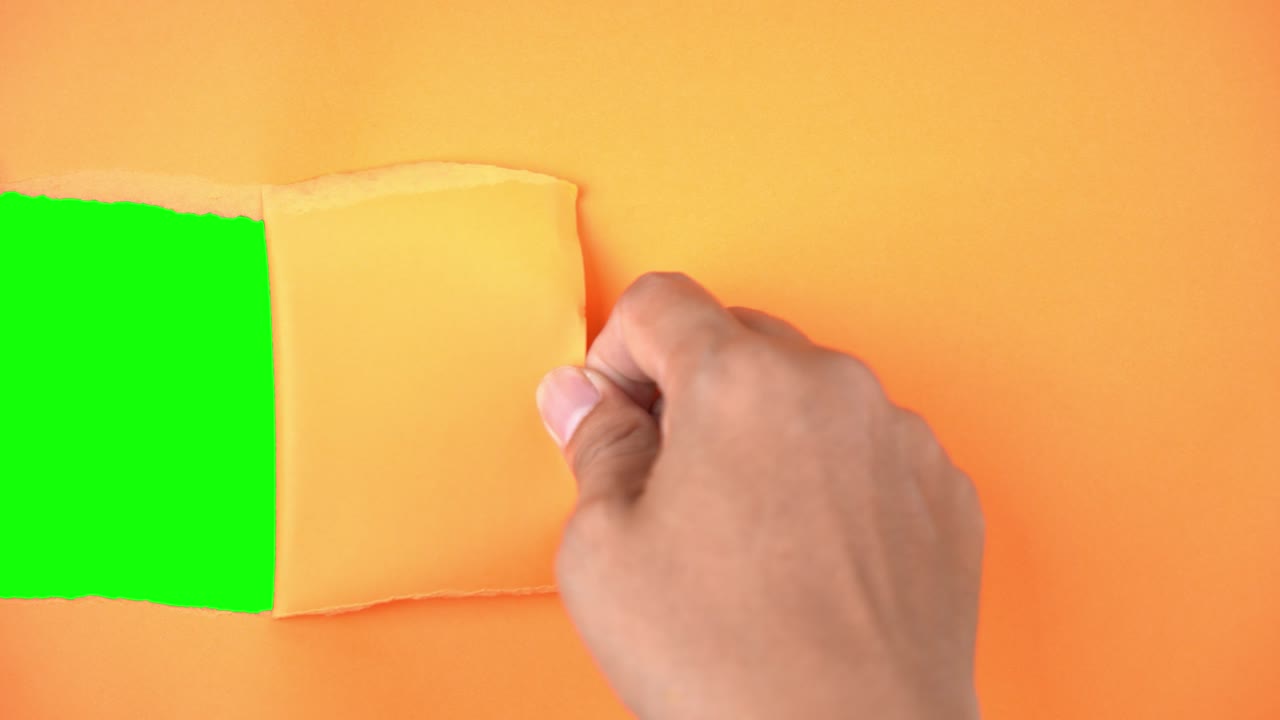 Man hand tears a paper and reveal green background
