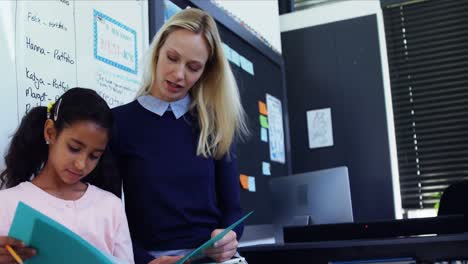 Teacher-helping-schoolgirl-with-her-homework-in-classroom