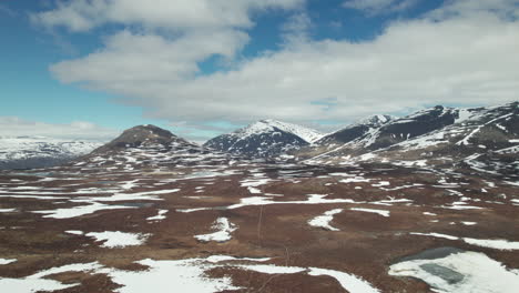aerial view of small path in a stunning serene swedish mountain landscape, snow on the kungsleden in the abisko national park, drone rising up