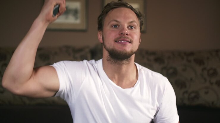 Excited Man Cheering and Gesturing with Remote Control