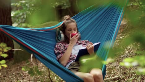 excursionista acostado en la hamaca y leyendo un libro