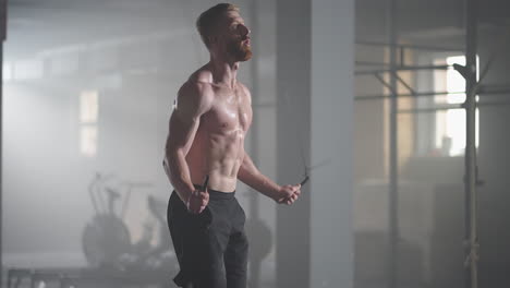 a young athletic man with prominent muscles jumps on a rope in the gym in slow motion