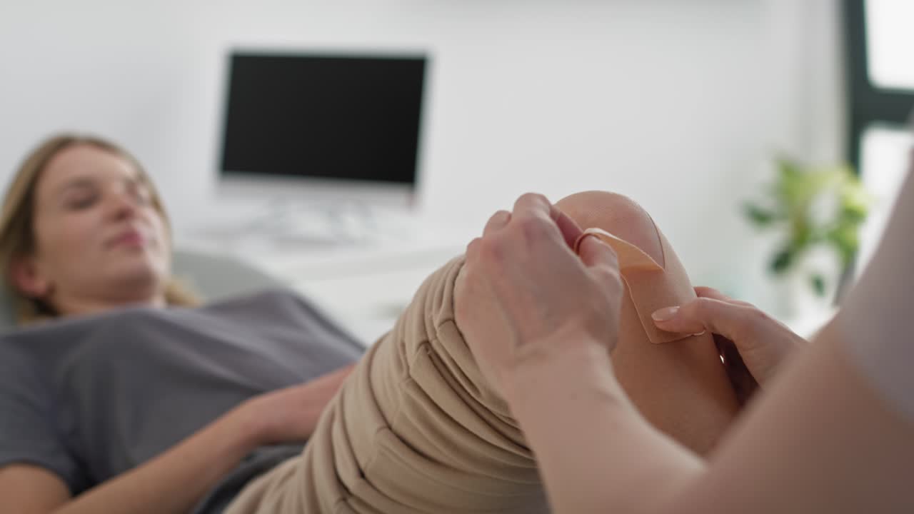 Physical therapist applying kinesio tape to the patient's knee.