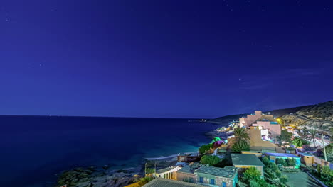 Time-lapse-shot-of-driving-cars-on-coastal-road-in-Morocco-during-blue-night-with-flying-stars-in-Africa