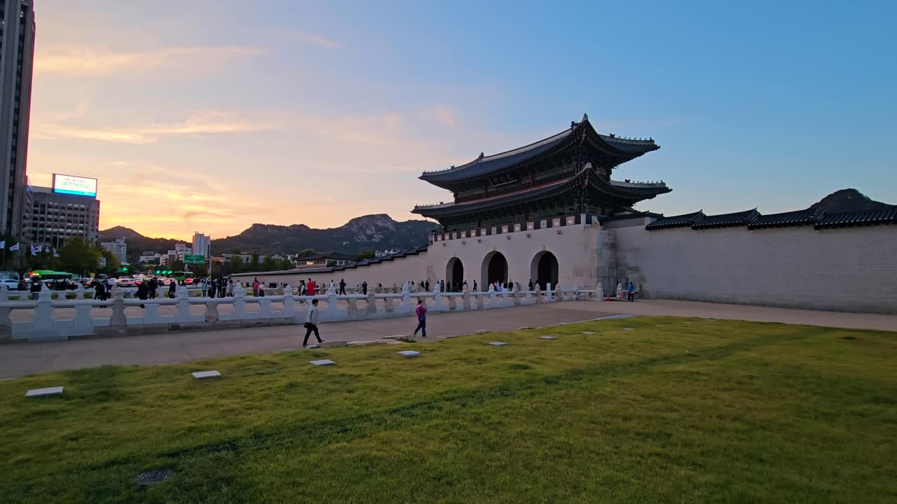 Tourists at Gwanghwamun Gate of Gyeongbokgung Palace in Seoul at Sunset - pan shot