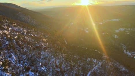 aerial footage of a forested mountain valley with a light coating of snow during winter in the appalachian mountains during sunset’s golden hour in winter