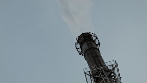 industrial factory pipe over a blue sky with loads of smoke from ground