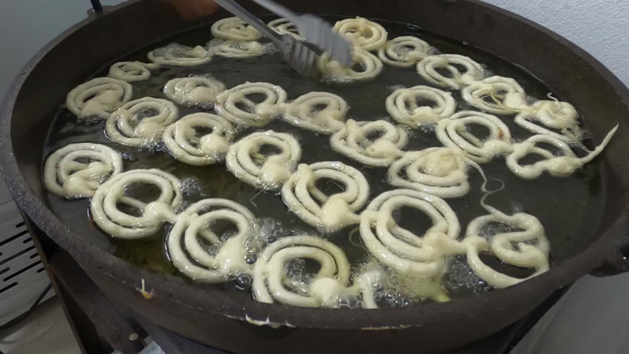 Raw jilapi deep frying 4k video clip.Jilapi making on a hot big pan.Jalebi, also known as jilapi, jilebi, jilipi, zulbia, jerry, mushabak, or zalabia, is a popular Indian sweet snack.