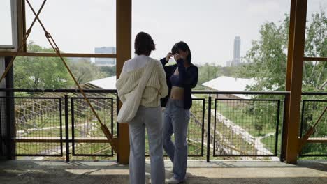two women in an outdoor photoshoot setting with city backdrop