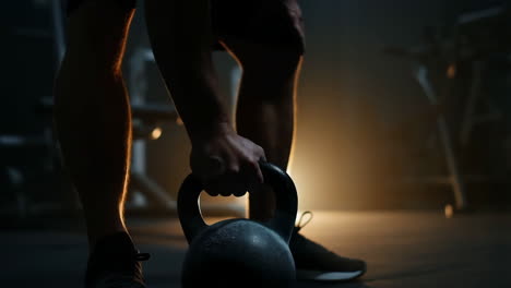 person preparing to lift a kettlebell in a dimly lit gym