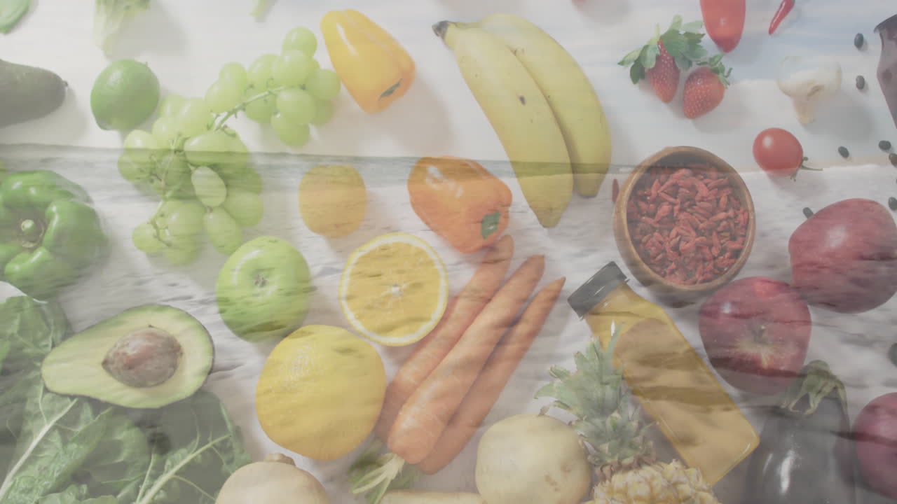 Fruits and vegetables arranged on table with overlay of ocean waves animation