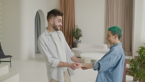 loving young couple in casual wear holding hands and dancing at home