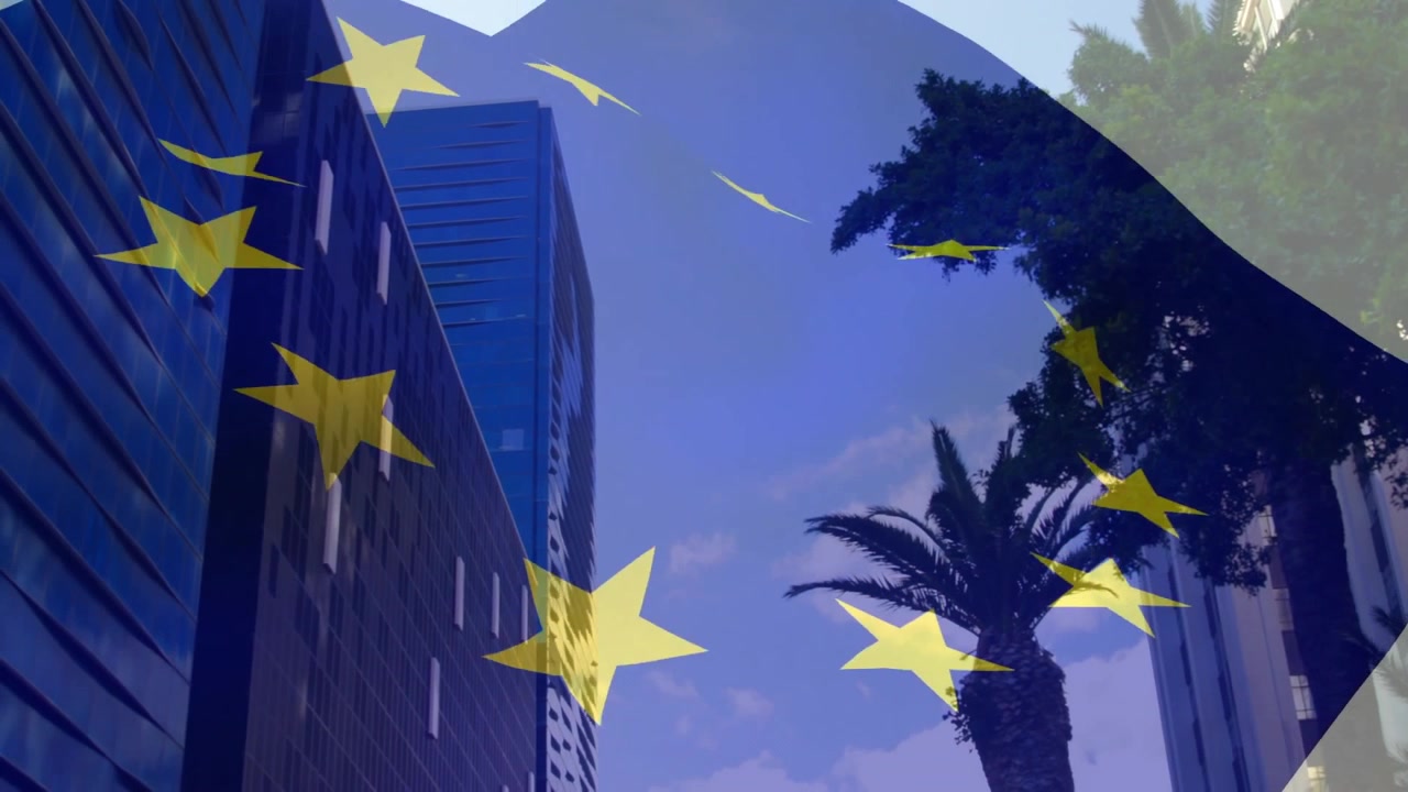 Sovrapposizione della bandiera UE che appare in dissolvenza su grattacieli cittadini, con stelle che sventolano e si spostano a simboleggiare l'unità.