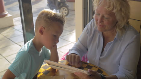 grandmother and grandson with pad in cafe