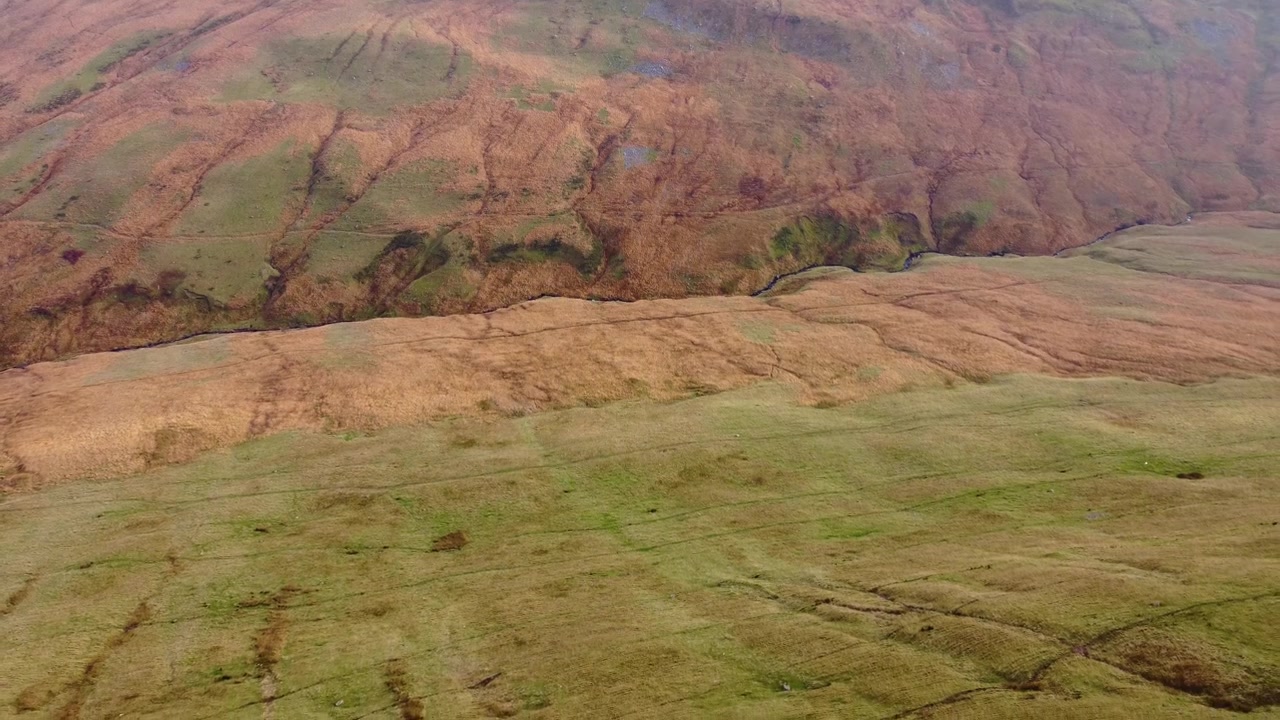 Ripresa aerea dall'alto con drone in allontanamento di una profonda gola tortuosa con sentieri su un paesaggio naturale nei Brecon Beacons. Luogo perfetto per escursioni e trekking 4K.