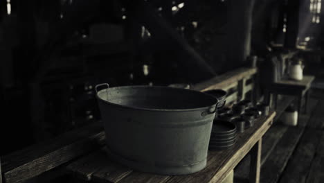 old metal bucket on wooden table in dark rustic setting with dishes