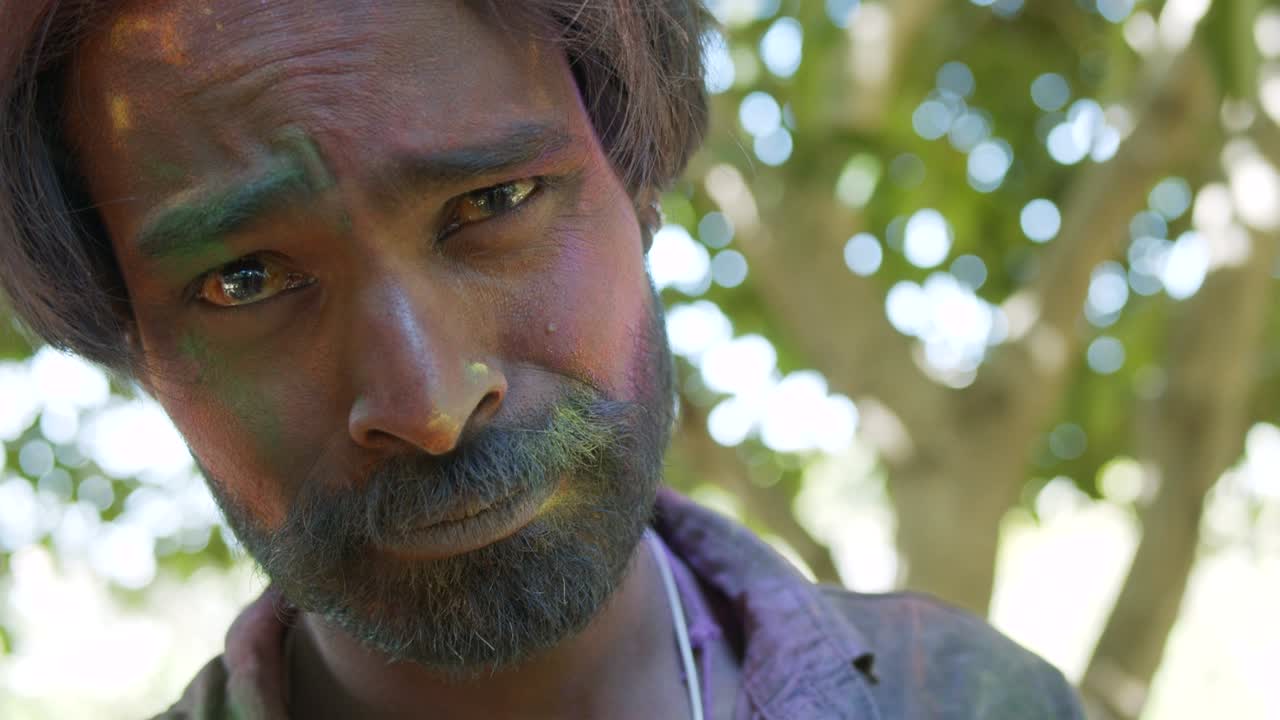 hombre indio de primer plano de la cara manchada con colores brillantes de holi