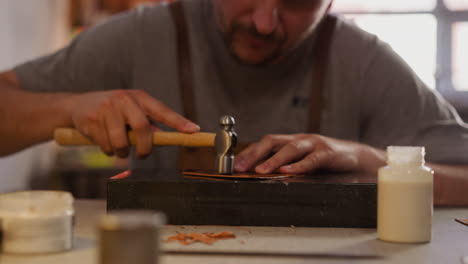 Concentrated-leathersmith-processes-material-at-table