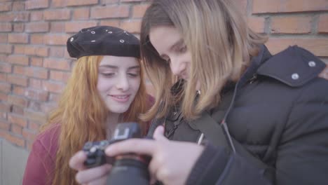 two friends have fun taking pictures in the street. the photographer and model checking one of the photos and they smile with the result