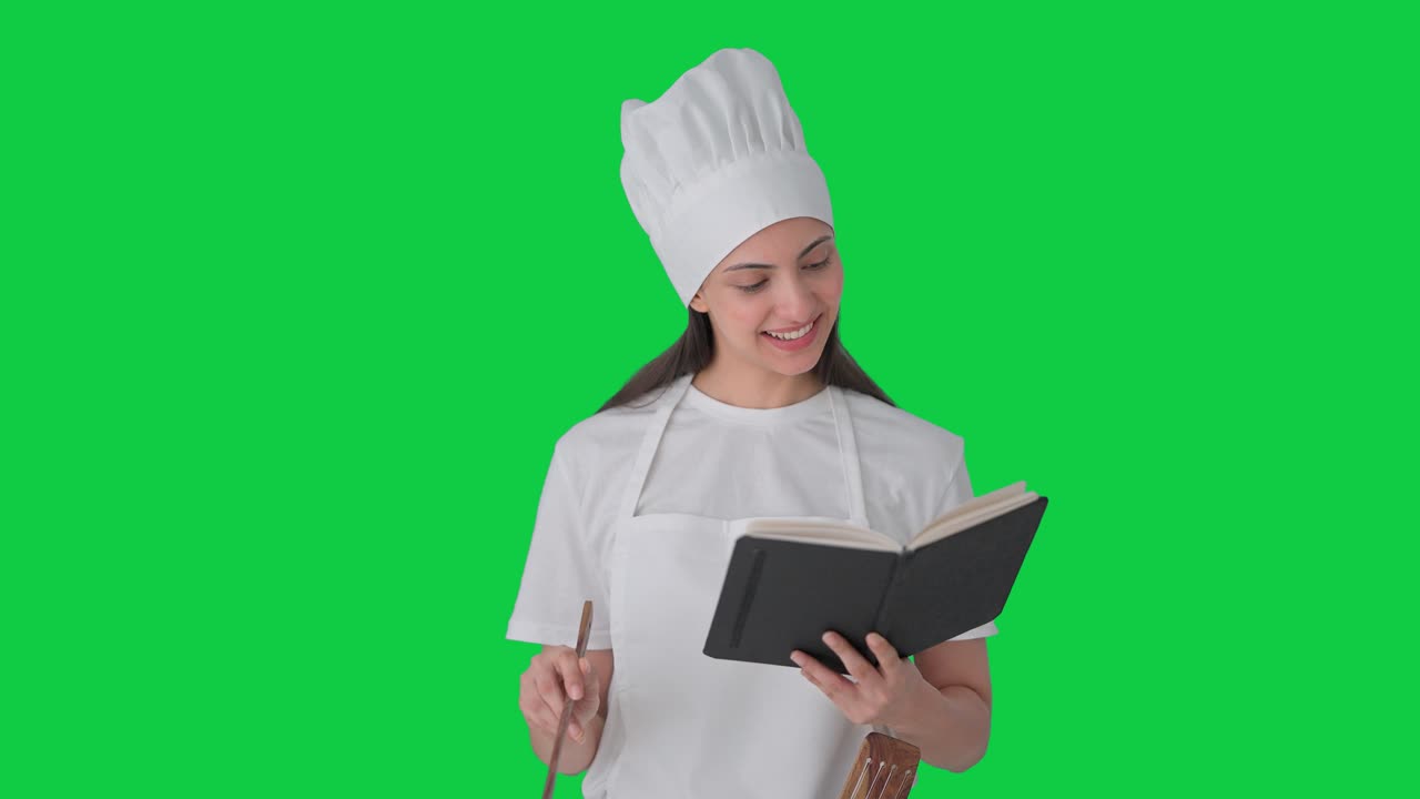 feliz india mujer chef profesional haciendo comida de libro de recetas pantalla verde