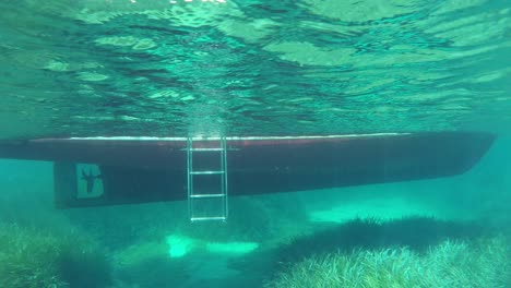 Vista-De-Un-Barco-Bajo-El-Agua-Por-Debajo-De-La-Línea-De-Agua-En-Aguas-Cristalinas