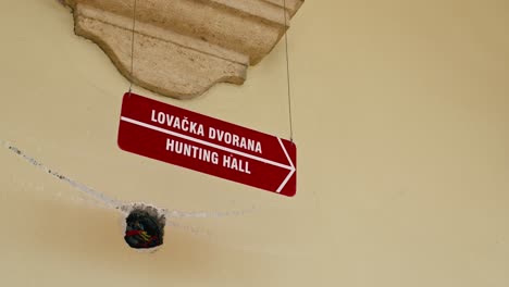 red directional sign to trakošćan castle's hunting hall, suspended on a textured yellow wall