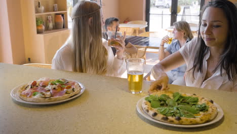 vorderansicht von frauen, die trinken und sich unterhalten, während sie an einer restaurantbar sitzen 1