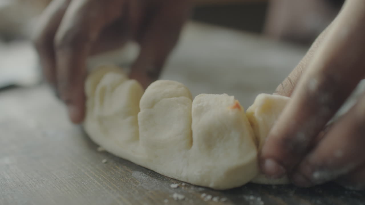 Hands shaping dough with filling for baking