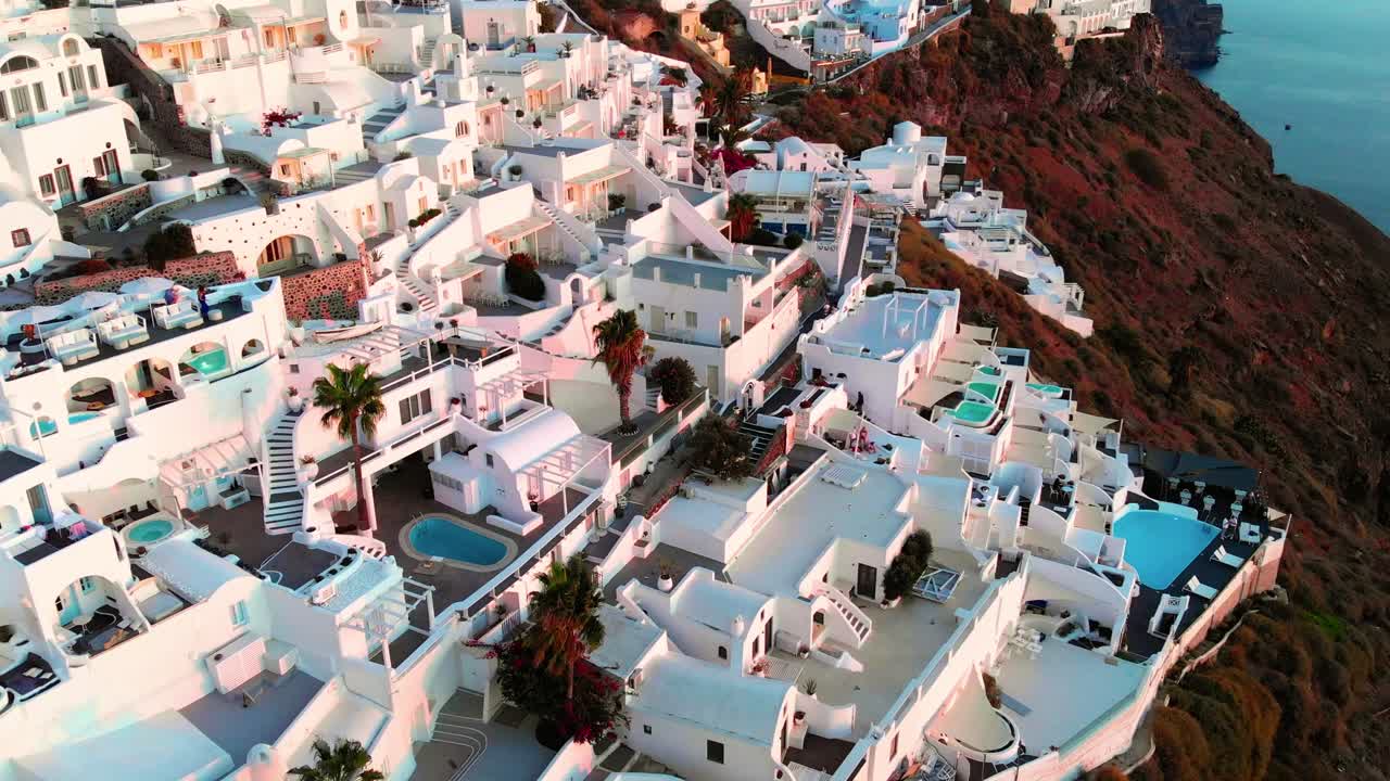toma aérea cinematográfica del famoso pueblo de oia en santorini, grecia, al atardecer