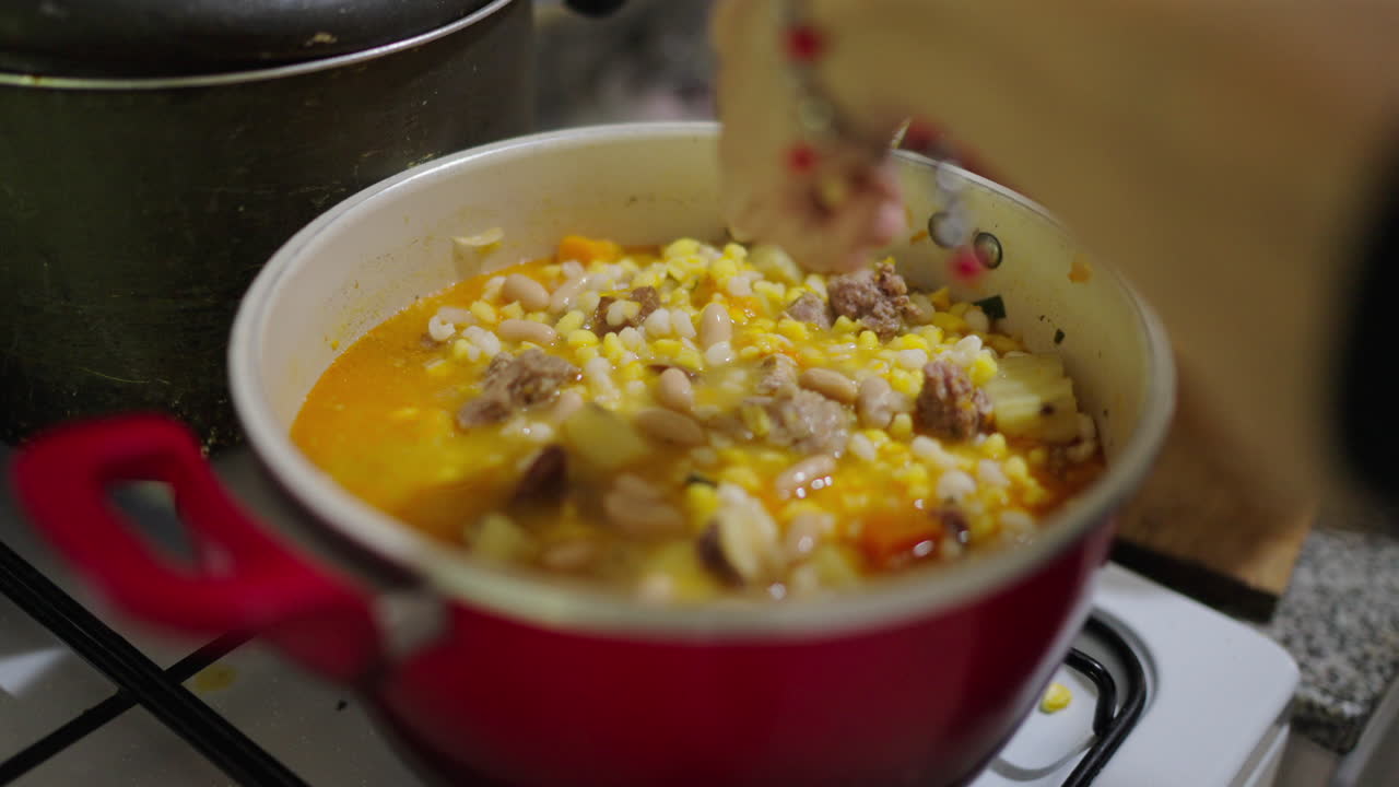 Rustic kitchen scene during cooking hearty Locro Argentino corn stew being prepared using fresh ingredients.