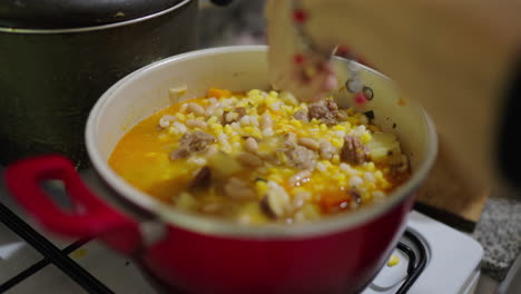 rustic kitchen scene during cooking hearty locro argentino corn stew being prepared using fresh ingredients.