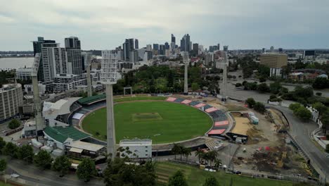 Drone-circles-around-WACA-cricket-sports-stadium-in-Perth-with-the-view-of-skyline-buildings-in-the-background,-Western-Australia