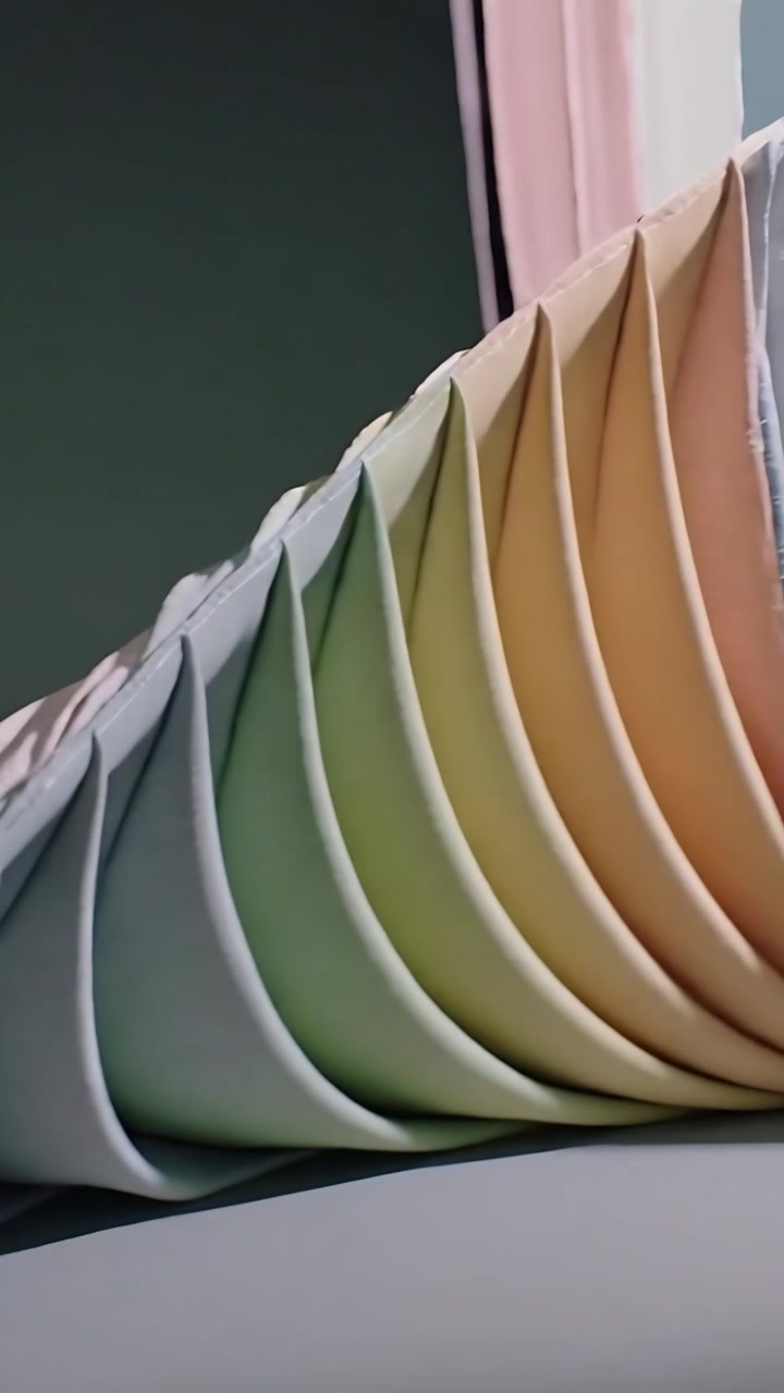 Video verticale: Panoramica della telecamera che rivela un arco in tessuto plissettato su un tavolo da studio, mostrando le cuciture interne.
