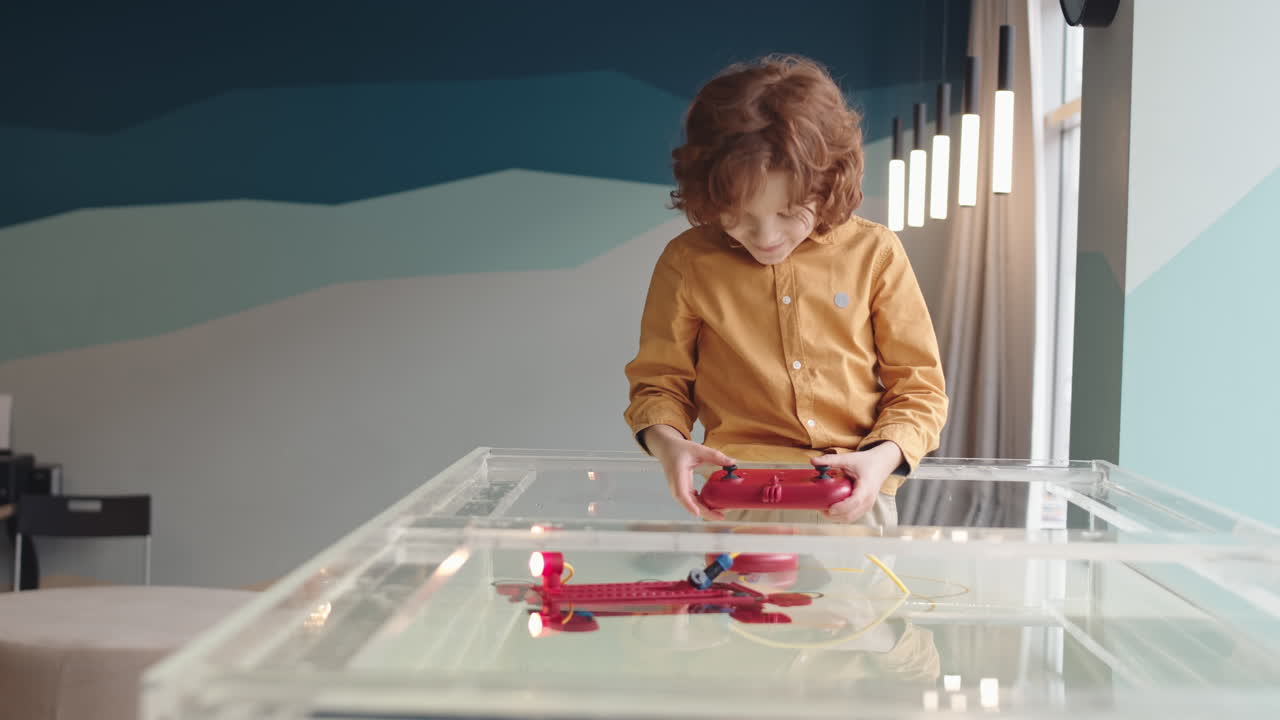 Red-haired Boy Controlling Robo Boat with Joystick