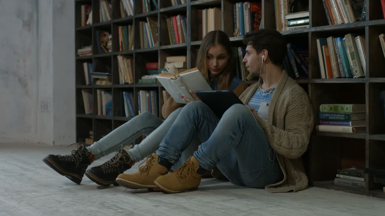 una pareja de hipsters aprendiendo juntos en la biblioteca.