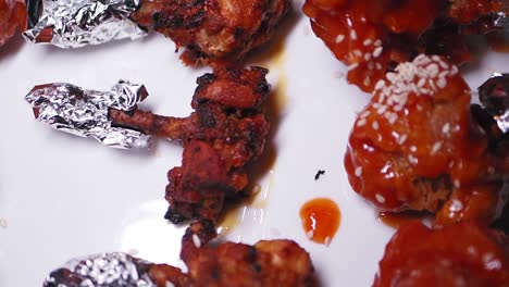 close-up of fried chicken lollipops with sauce and sesame seeds