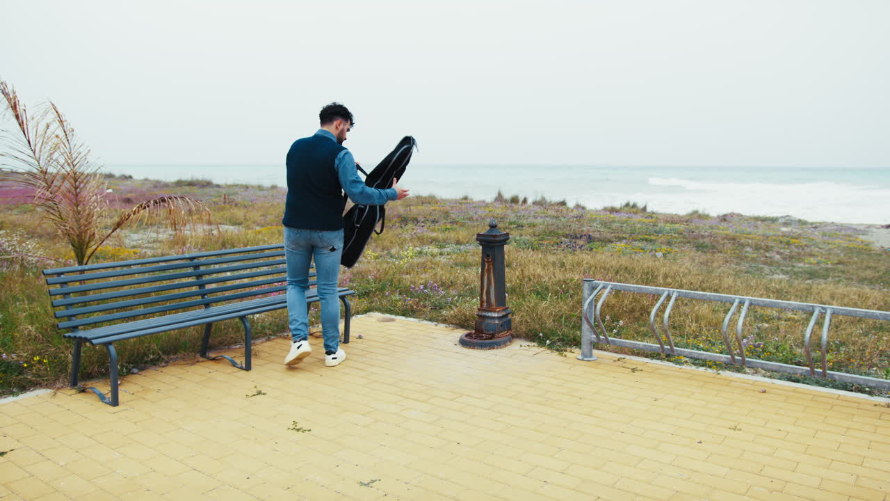 Man with guitar case at the beach