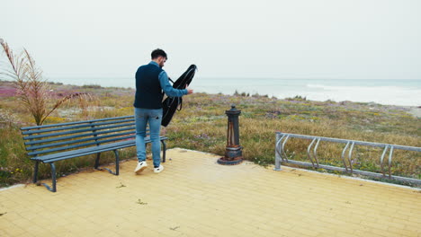 man with guitar case at the beach