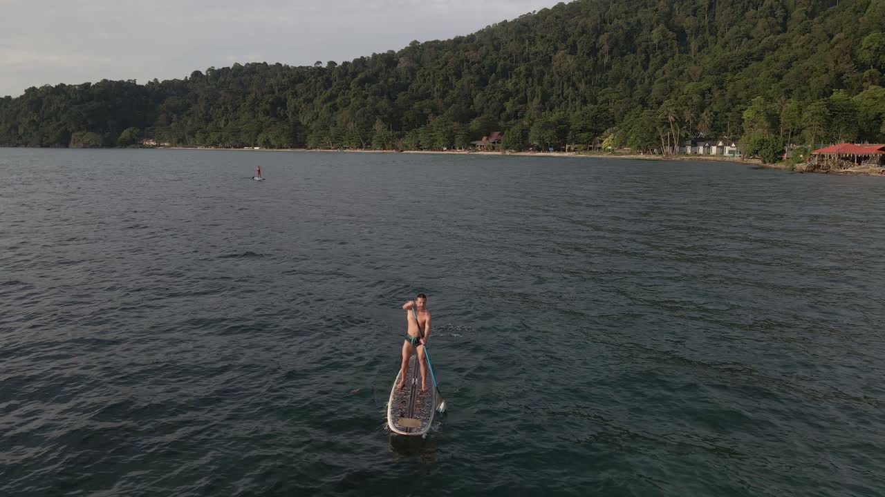 태국의 해변과 해안선이 있는 청록색 열대 맑은 바다에서 수프 패들 보드에서 운동하는 사람의 공중 드론 조감도