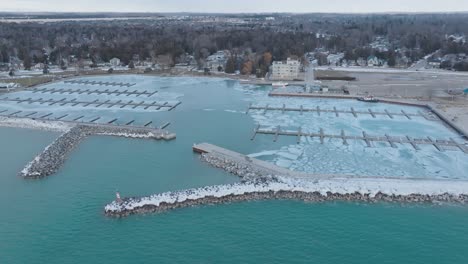 icy port elgin harbor with frozen piers, blue water, and coastal town backdrop, at dusk, aerial view