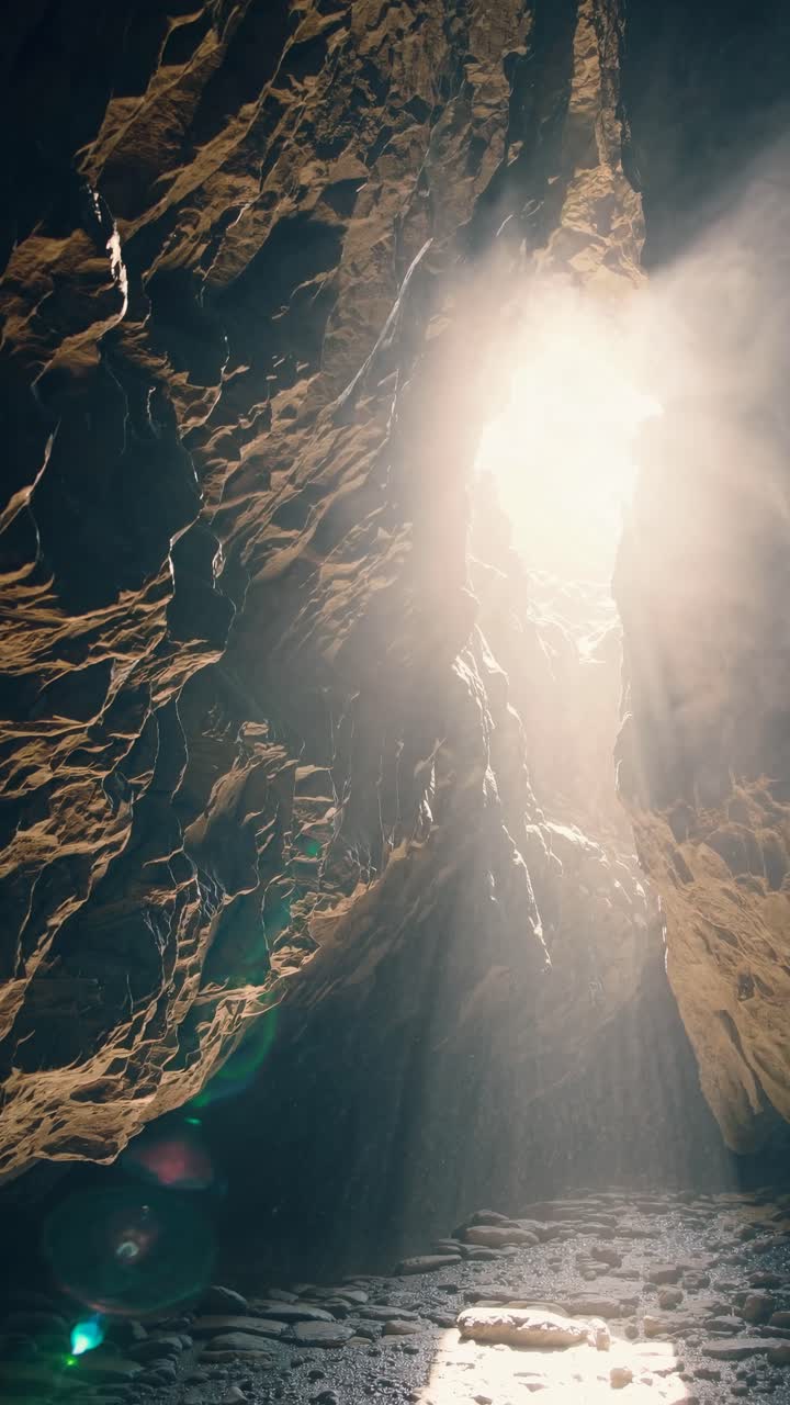 A dramatic upward angle captures sunlight streaming into a rocky cave, creating a mystical