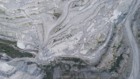 aerial panorama of vast aggregate quarry carved into terraced grey stone with looping haul tracks illustrating large-scale minerals extraction and heavy industry