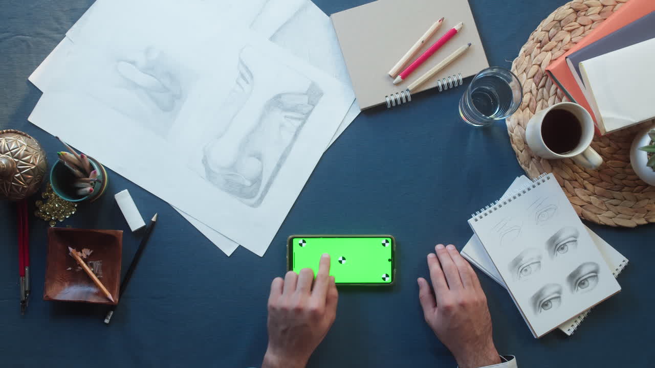 Hands Using Smartphone with Green Screen on Artist's Desk