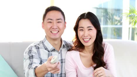 Happy-couple-eating-popcorn-and-watching-tv