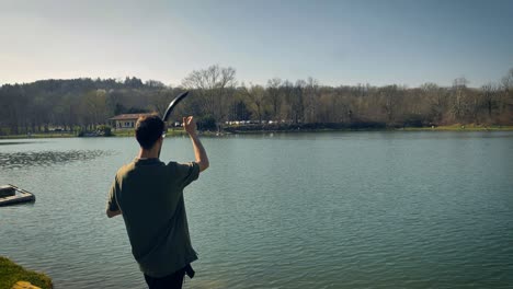 man fishing for carp tosses bait into the water to attract fish to his line-1