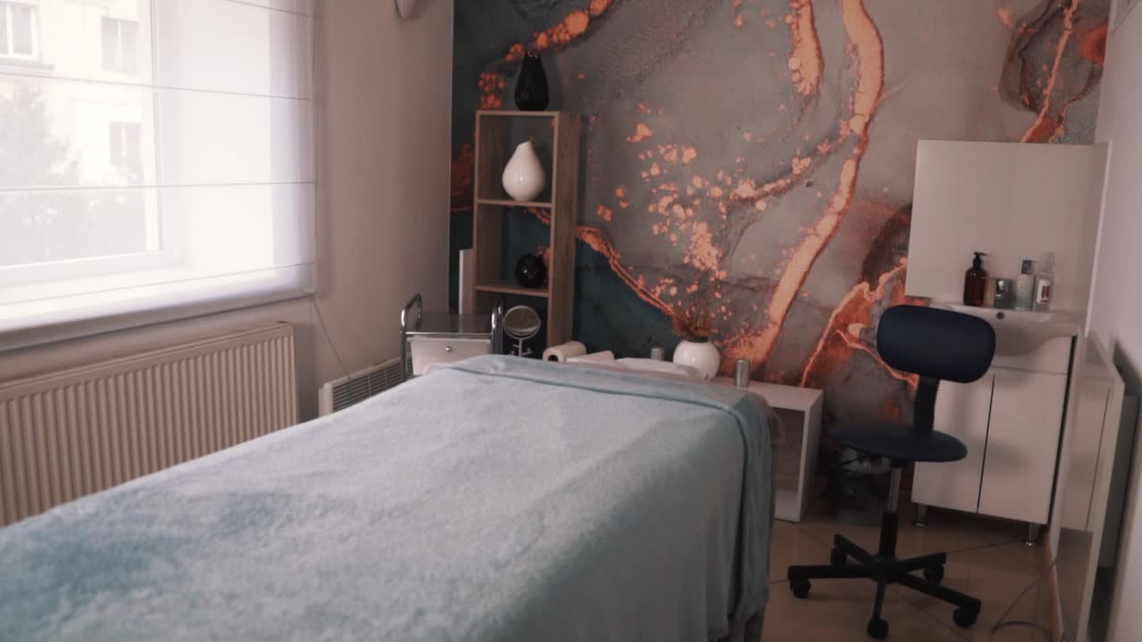 vista general de una sala de masajes con un hermoso papel pintado y una mesa de masajes