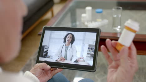 senior caucasian man using tablet for online consultation with biracial female doctor, slow motion