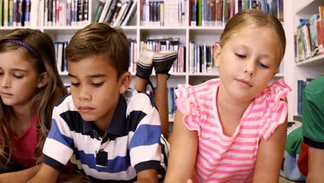 teacher and kids lying on floor reading book in library